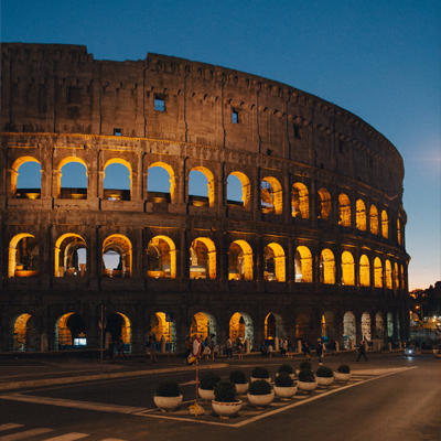 Colosseum at sunset in Rome, Italy, illuminated with golden lights.